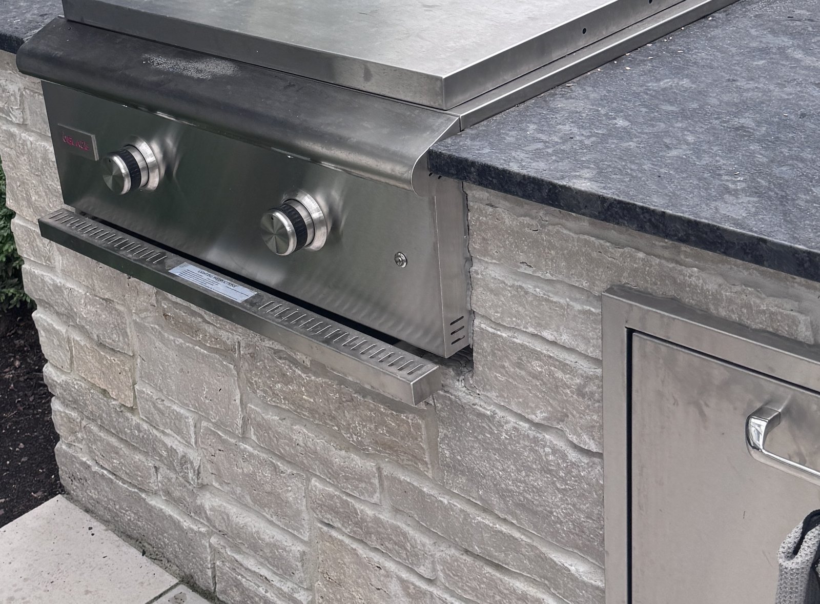 Blaze built-in griddle with its stainless lid closed, set into a stone island