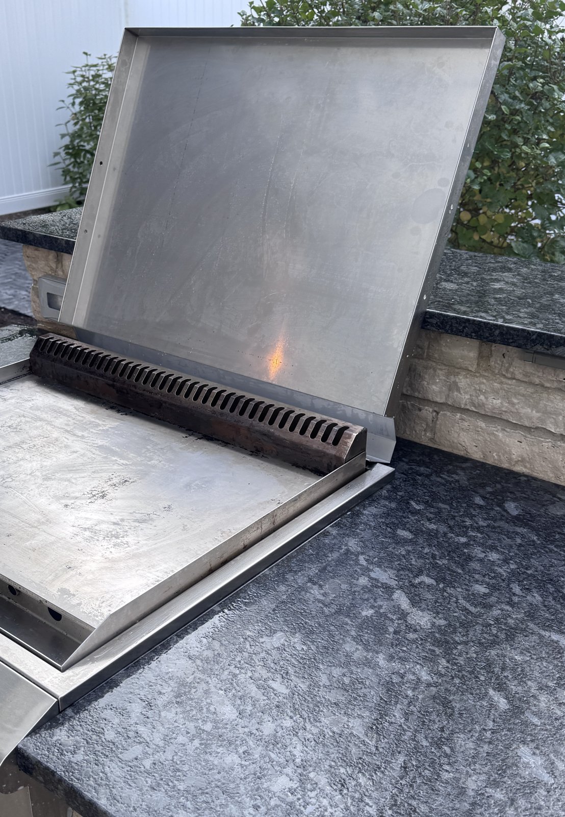 Cleaned Blaze drop-in griddle with the lid open in a stone outdoor kitchen